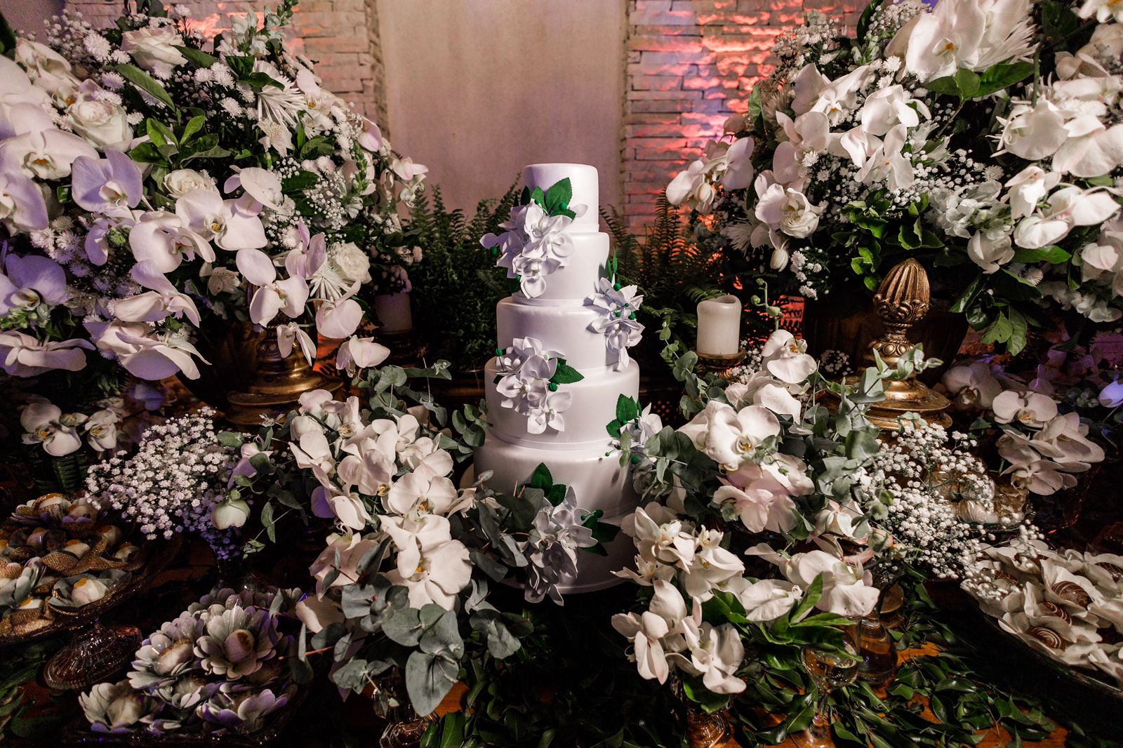 Mesa de bolo de casamento com flores brancas e folhagem